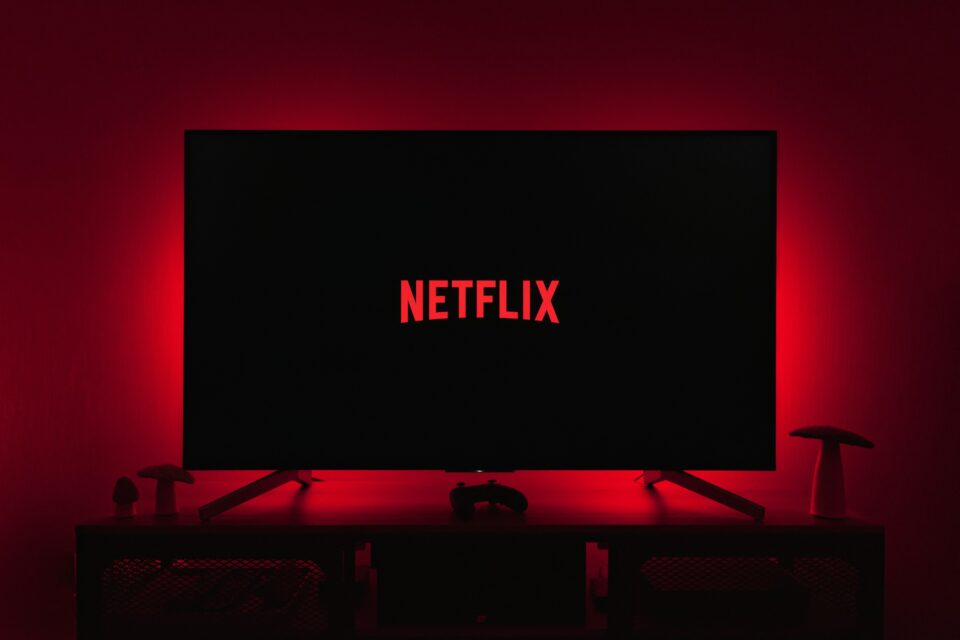 A large TV displaying the Netflix logo, lit by red ambient light in a dark room